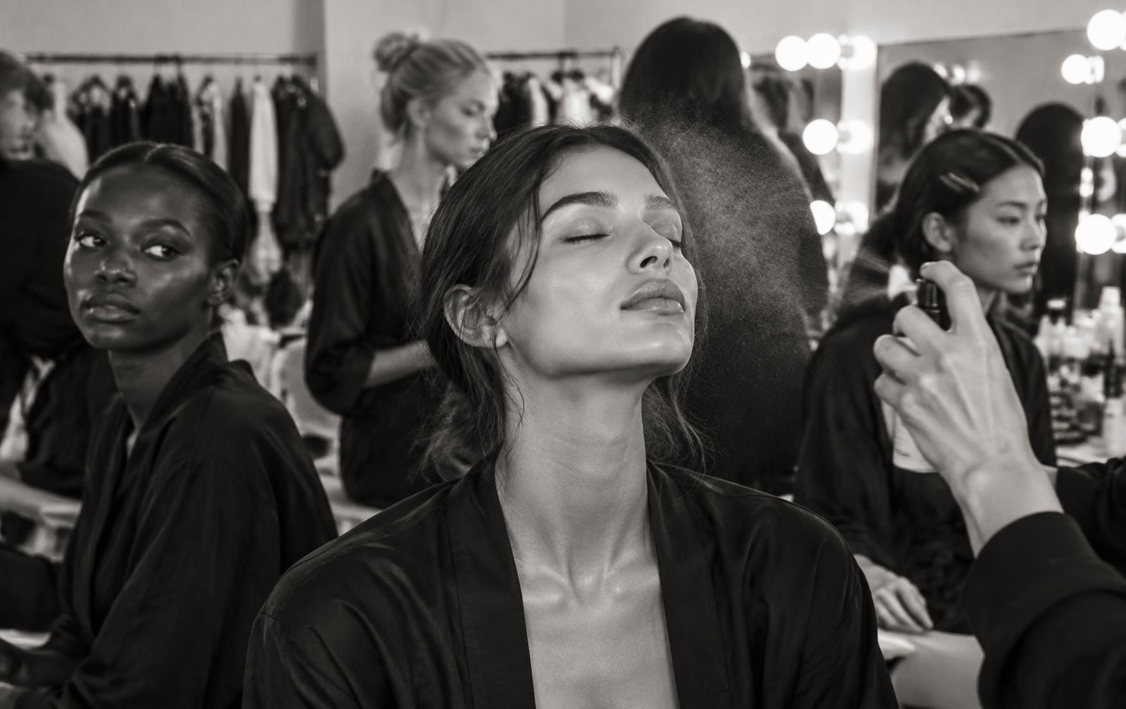 Black-and-white backstage beauty scene with models preparing their skin
