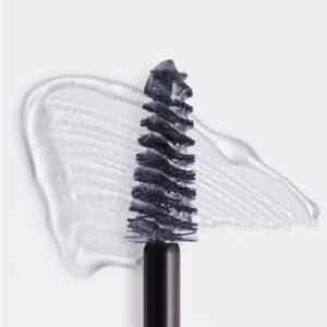 A close-up of the Revitalash Hi-Def Brow Gel- Clear spoolie brush, with clear gel smeared beneath it on a white surface.