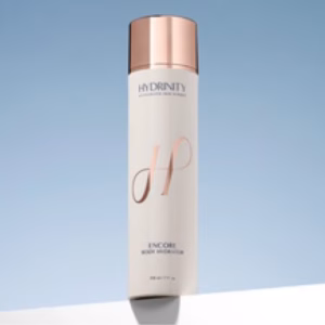 A white 7oz bottle of Hydrinity Body Hydrator, topped with a rose gold cap, is set on a white surface against a light blue background.