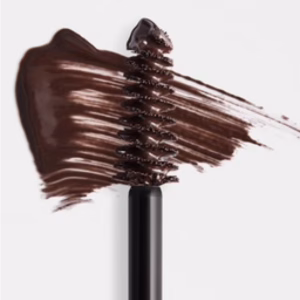 A close-up of the Revitalash Brow Gel in Dark Brown with its applicator wand, and brown gel smeared in the background on a white surface.