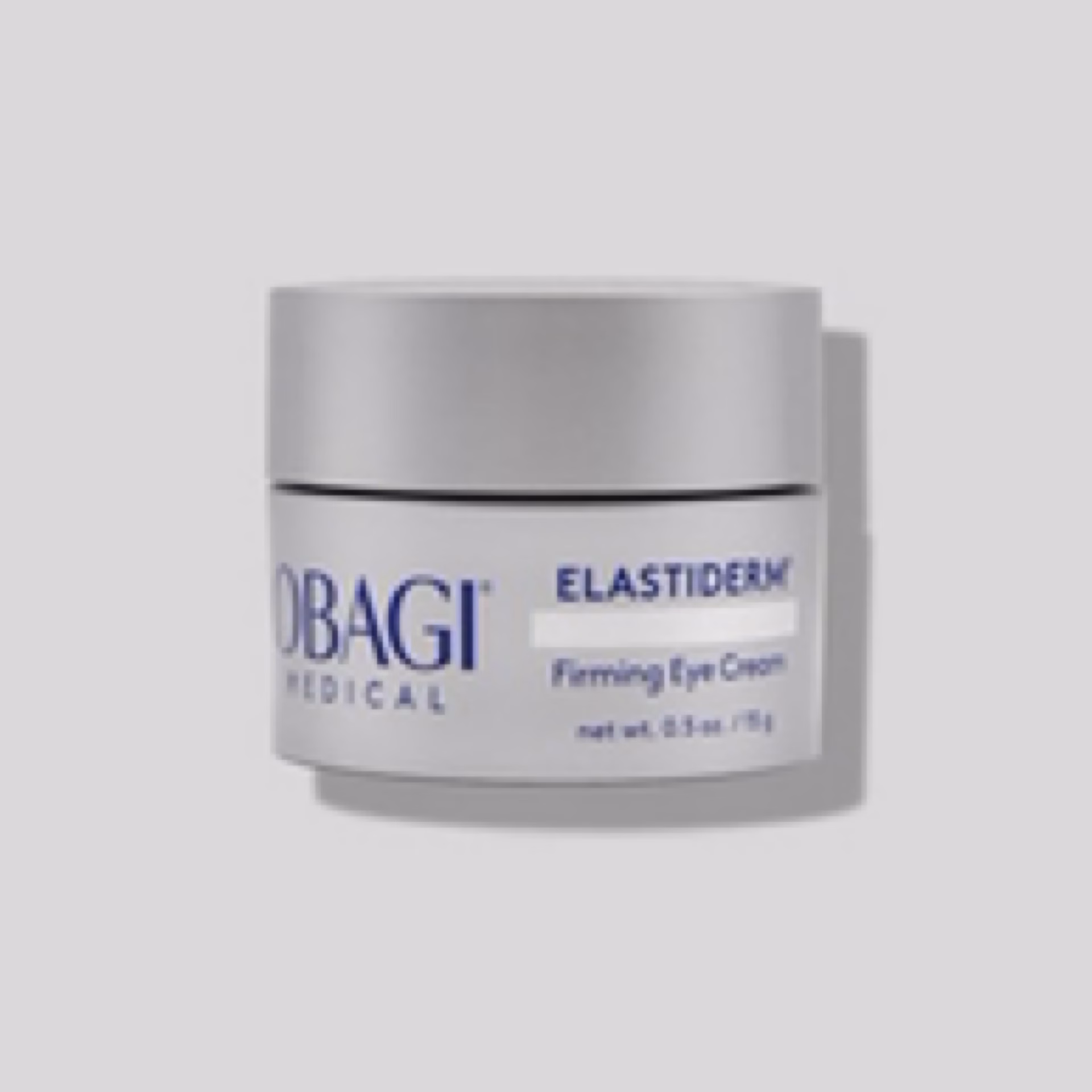 A small silver jar of Obagi Elastiderm Eye Cream is shown against a plain light gray background, with the label displaying the product name and a net weight of 0.5 oz (15 g).