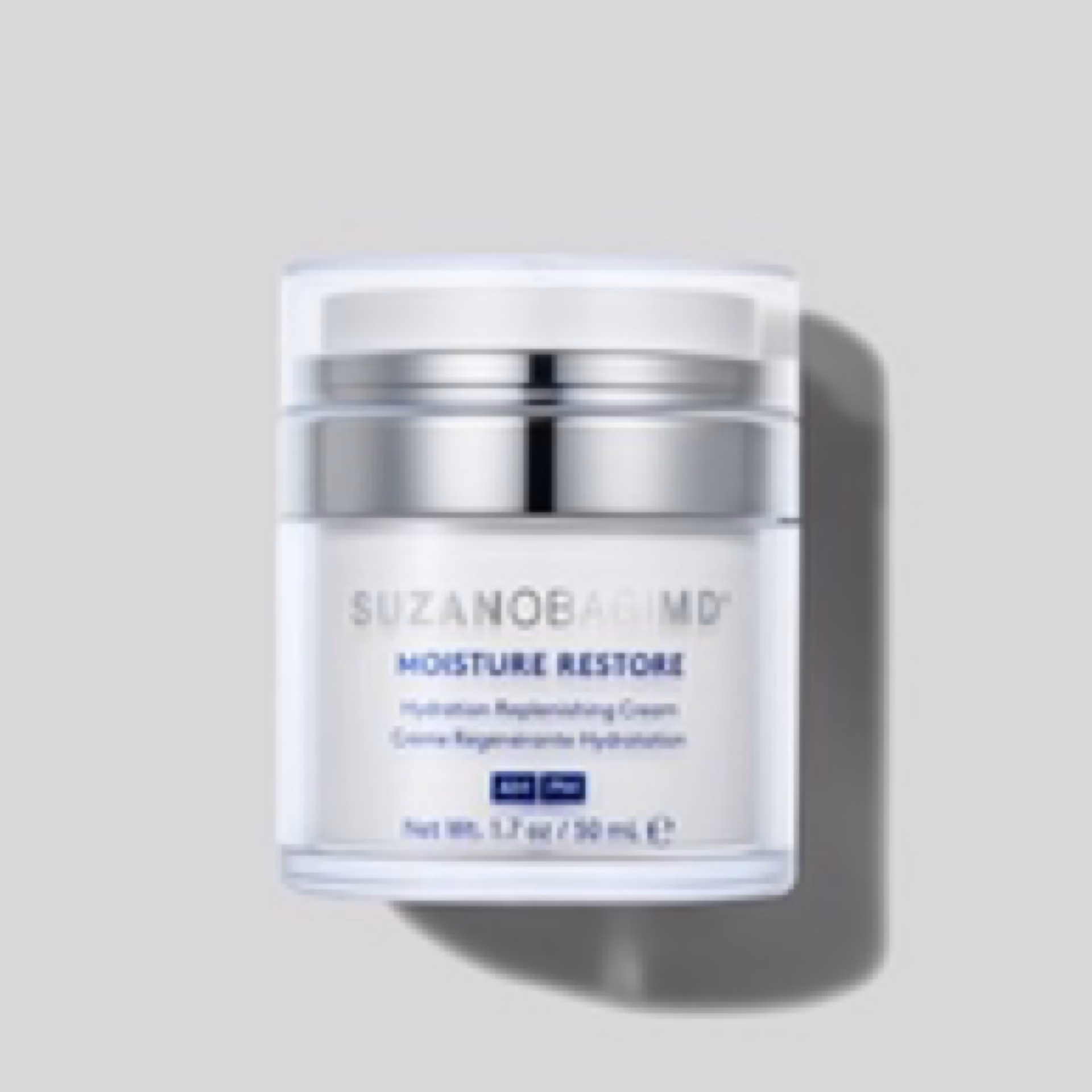 A clear and white jar of Suzan Obagi moisture restore is shown on a light gray background. The label identifies it as a hydration replenishing cream in a 50 mL container.
