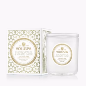 The Voluspa Eucalyptus 9.5oz Candle is displayed in a clear glass jar next to its matching decorative white and gold patterned box with a round label.