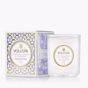 The Voluspa Mountain Lavender & Chamomile 9.5oz Candle comes in a white glass jar beside its gold-accented lavender floral box.